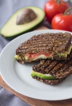 a sandwich on a plate with avocado and tomatoes