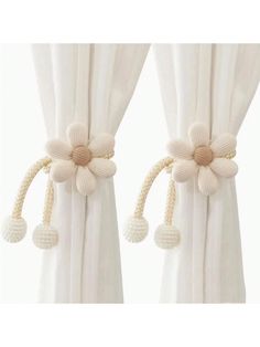 two white curtains with flower decorations hanging from them