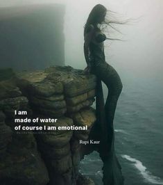 a woman standing on top of a cliff next to the ocean