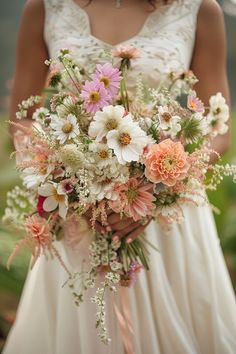 a woman holding a bouquet of flowers in her hands and wearing a white wedding dress