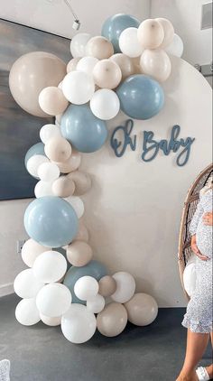 a pregnant woman standing next to balloons and a sign that says k baby on it