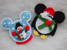 two crocheted mickey mouse and snowman coasters on a white surface,