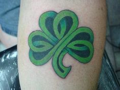 a green clover tattoo on the leg