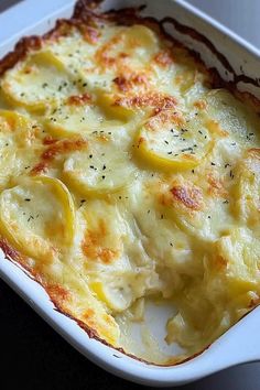 a casserole dish with potatoes and cheese in a white dish on a table