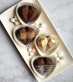 four heart shaped chocolates on a plate with marshmallows and sea salt