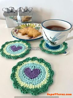 three crocheted coasters sitting on a table next to a cup of tea