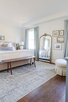 a bedroom with a large bed and blue drapes on the windowsill, along with a white rug