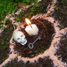 a candle that has been placed in the dirt with a skull and wrench next to it