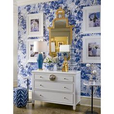 a blue and white room with pictures on the wall, a chest of drawers and a mirror