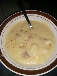 a white bowl filled with soup on top of a black table next to a spoon