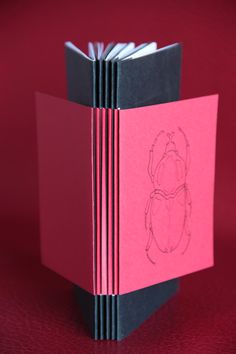 an open book with a drawing of a bug on the front and back pages in red paper