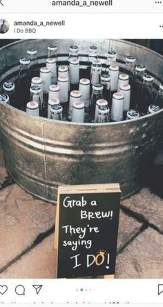 a metal bucket filled with lots of bottles next to a sign that says grab a brew they're saying i do