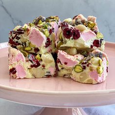 a pink plate topped with pieces of cake covered in frosting and cranberries