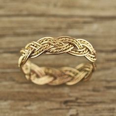 a gold braid ring sitting on top of a wooden table