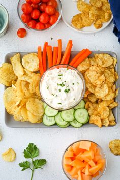 a platter with carrots, celery, cucumbers and chips