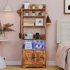 a bedroom with pink walls and a wooden bookcase filled with books on top of it