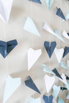 blue and white origami birds hanging from strings on the wall with paper streamers