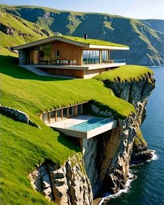 the house is on top of a cliff overlooking the ocean and grassy area with a swimming pool