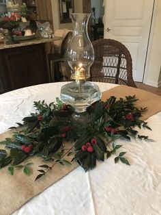 a candle is lit on top of a table with greenery and berries around it