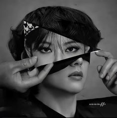 a black and white photo of a woman holding scissors to her face with both hands