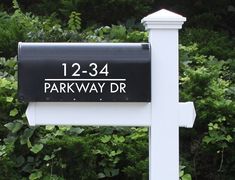 a black and white mailbox sitting in front of some bushes