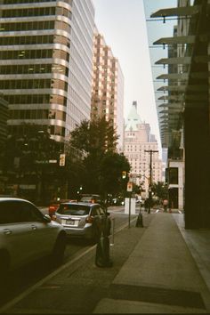 cars are parked on the side of the road in front of tall buildings and skyscrapers