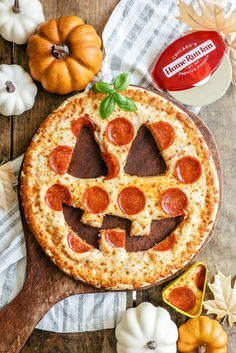 a pizza with pepperoni and cheese in the shape of a smiley face on a wooden board