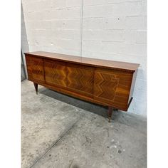 a large wooden dresser sitting on top of a cement floor next to a white brick wall