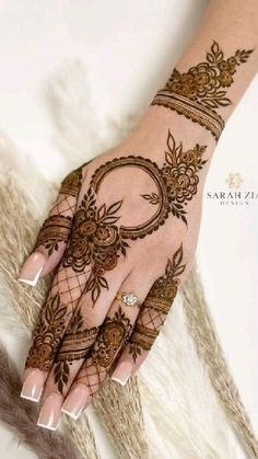 a woman's hand with henna tattoos on her left arm and hands, decorated with flowers