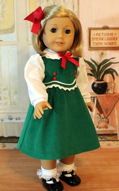 a doll with blonde hair wearing a green dress and black shoes, standing on a wooden floor