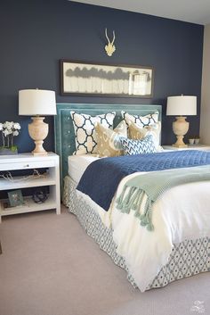 a bedroom with blue walls and white bedding, two lamps on either side of the bed