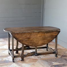 an old wooden table sitting on top of a hard wood floor next to a wall