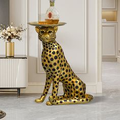 a gold leopard statue with a tray on its head sitting in front of a white wall