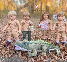 four dolls are posed in front of a toy alligator and other toys on the ground