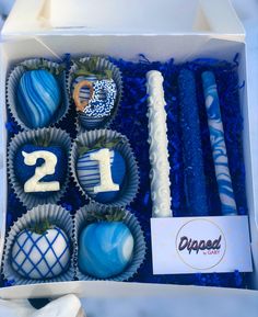 a box filled with blue and white chocolates next to two birthday candles on top of each other