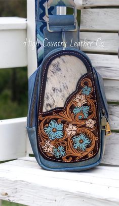 Here's the super popular sling bag with an added tooled leather patch. This patch features a hand tooled floral design with a speckled black and white cowhide inlay. The sling bag is a gorgeous blue gray color with an adjustable strap. Sling bag has two pockets, the front pocket is smaller and has some card slots, the rear pocket is larger and can fit all the necessities: phone, wallet, keys, check book, etc. Sling bag measures 5"x 9" x 3" PLEASE READ: This item is for pre-ordering, and is made to order! Once purchased, this item will take approximately two weeks to re-create. Item will be a close replica, but each one will have slight variances in color, carving, etc. as I am not perfect, and leather is not perfect either! Cowhide will also be different. The cowhide will still be black an Hand Tooled Blue Crossbody Bag, Artisan Blue Leather Bag, Hand-tooled Blue Crossbody Shoulder Bag, Blue Hand Tooled Leather Shoulder Bag, Blue Leather Hand Tooled Shoulder Bag, Hand Tooled Blue Leather Shoulder Bag, Blue Artisan Leather Shoulder Bag, Artisan Blue Leather Shoulder Bag, Blue Leather Artisan Shoulder Bag