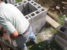 a man standing next to a pile of cinder blocks