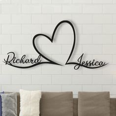 a living room with a couch and two pillows on top of the sofa, in front of a brick wall that says richard & jesica