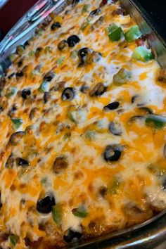 a casserole dish with black olives, green peppers and cheese on it