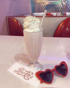 two heart shaped glasses sitting on top of a table next to a milkshake