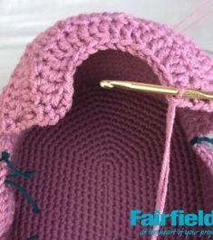 a pink crocheted bag with a hook on it's end and the handle is holding a knitting needle