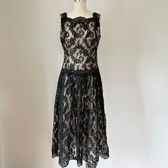 "1960s stunning black lace illusion cocktail dress with sheer beige lining. Perfect for any formal occasion or party, it features a drop waist design and embodies the iconic fashion of the 60s, while still remaining timeless and chic. The intricate lace detailing adds a touch of femininity and elegance. It is sleeveless with a back zipper and depending on your height, is mid calf or ankle length.  Small to medium size. The dress form is a 0 to 2. Please check measurements carefully. Measurements with an inch of room for comfort: Bust up to: 37\" Waist up to: 29\" Hips up to: 39\" Exact measurements are taken flat to compare to a garment that fits well: Length: 47\" Bust: 19\" Waist: 15\" Hips: 20\"  Designer/ Brand/ Label: unmarked The condition is excellent. It has been  hand washed and i Tea Length Lace Dress With Lace Trim For Party, Tea-length Lace Dress With Lace Trim For Party, Sleeveless Lace Trim Vintage Party Dress, Sleeveless Vintage Dress With Lace Trim For Party, Elegant Lace Bodice Dress For Vintage Events, Elegant Dress With Lace Bodice For Vintage Events, Elegant Lace Vintage Party Dress, Sleeveless Lace Dresses For Vintage Events, Elegant Lace Dress With Lace Bodice For Vintage Events