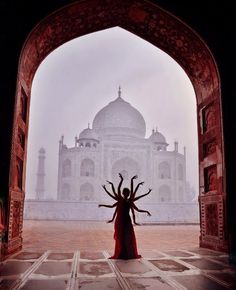 a woman standing in front of an archway with her arms outstretched