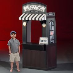 a young boy standing in front of a train ticket booth