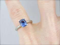 This is a well proportioned ring, small in size but with excellent style and substance. The brightly polished sides have a great heft to them, and this is comfortable on the finger, with a rich feel. We've set the center with a stunning Ceylon Sapphire! This gemstone has a wonderful dusty indigo shade, not quite purple but too deep to truly be called blue. We love the cut of this rare gem, which brings plenty of life in to the stone! Metal: 14K White Gold Gem: Ceylon Sapphire, Blue with Purple F Luxury Minimalist Sapphire Solitaire Ring, Luxury Minimalist Solitaire Sapphire Ring, Simple Solitaire Engagement Ring, Ceylon Sapphire, Rare Gems, Sapphire Engagement, Sapphire Blue, Ring Ring, Solitaire Engagement