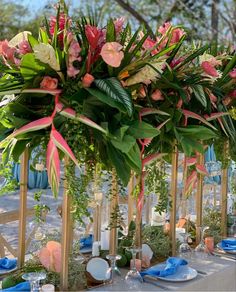 an arrangement of flowers and greenery on a table at a wedding or event with place settings