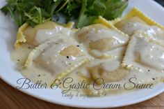 a white plate topped with ravioli covered in gravy next to a salad