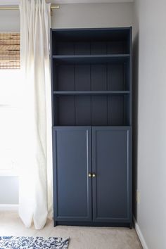 a blue bookcase sitting next to a window in a room with carpet and curtains