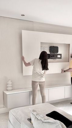 two people standing in front of a tv with their hands on the back of it