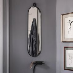 a bathroom with a mirror, coat rack and two pictures on the wall next to it